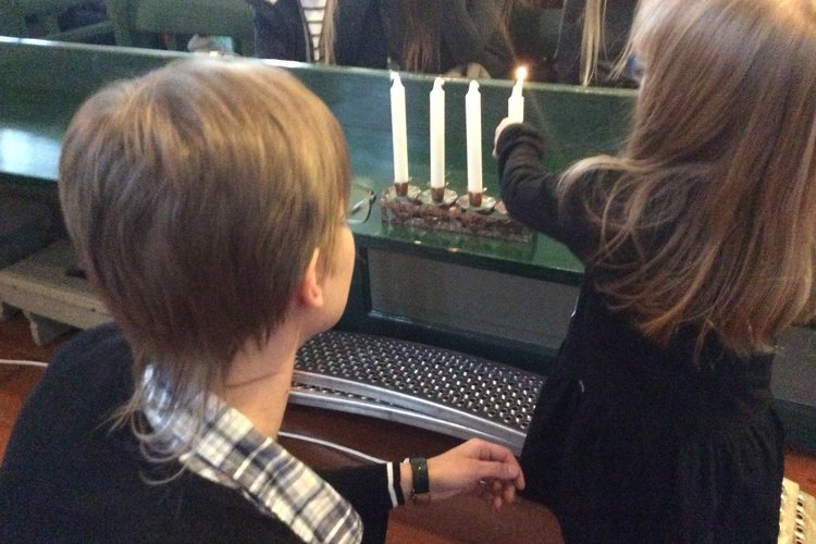 Oona sytyttää adventtikynttilää perhekirkossa.